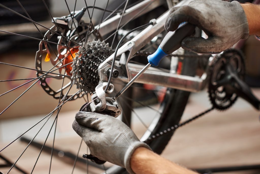 Male mechanic working in bicycle repair shop using tools